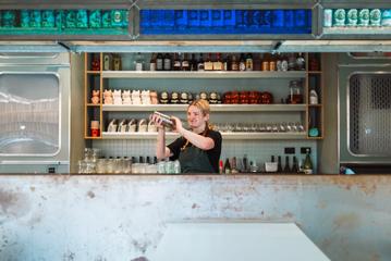 A bartender shakes a cocktail behind the bar at Mr Go's.