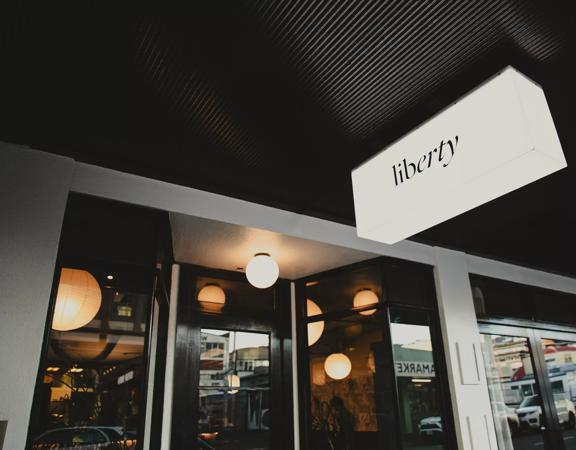 The storefront of Liberty, a restaurant in Te Aro Wellington. It's a white building with black accents and six circular ceiling lights. 