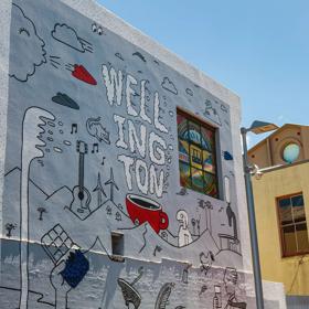 A grey, white and red, doodle-inspired street art mural on a Te Aro, Wellington building.