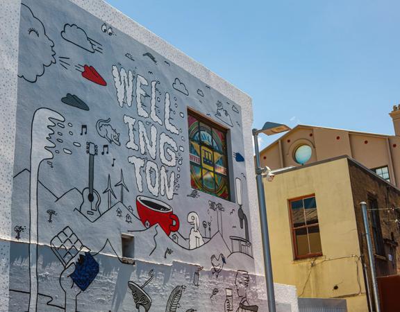 A grey, white and red, doodle-inspired street art mural on a Te Aro, Wellington building.