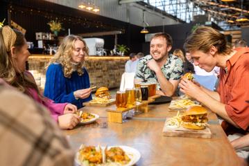 Group of people laughing whilst sitting at a table with beers and bar food at Aro Bar in Brewtown, Upper Hutt.