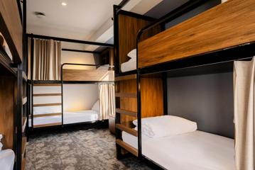 Inside a hostel room in Haka House, where bunk beds with ladders and curtains fill the room.