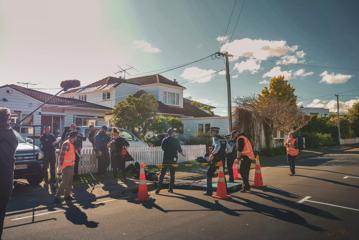 Behing the scenes of Wellington Paranormal, a comedic television series. The cast and crew are shooting a scene on a suburban street.