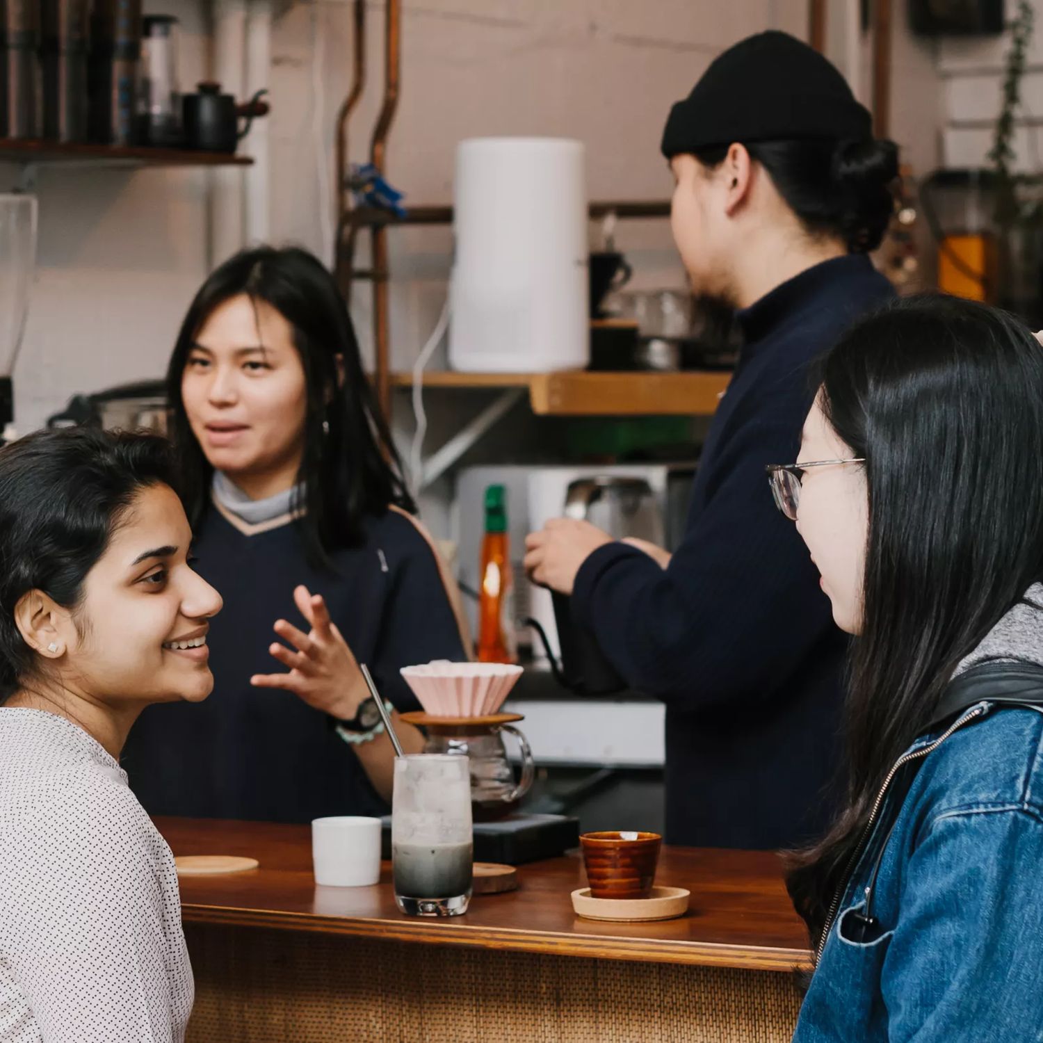 The front counter at Pour & Twist, a coffee bar in Te Aro Wellington. There are two people enjoying coffees, one is ordering and two workers are behind the counter.