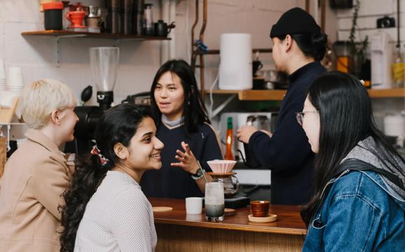 The front counter at Pour & Twist, a coffee bar in Te Aro Wellington. There are two people enjoying coffees, one is ordering and two workers are behind the counter.