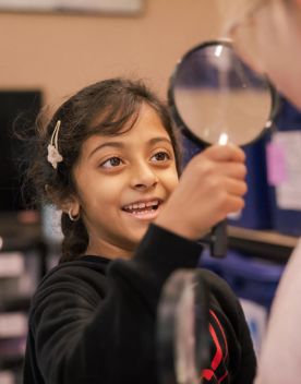 A child looks through a magnifying glass.