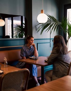 Two people sit across from one another at a small table at Koji.