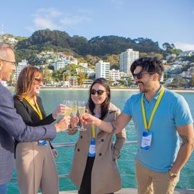 Delegates share a drink on a boat in the middle of Wellington harbour.