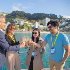 Delegates share a drink on a boat in the middle of Wellington harbour.
