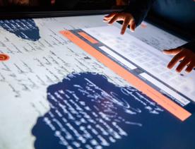 A childs hands typing on an interactive  He Tohu exhibition at  The National Library of New Zealand, Te Puna Mātauranga o Aotearoa.