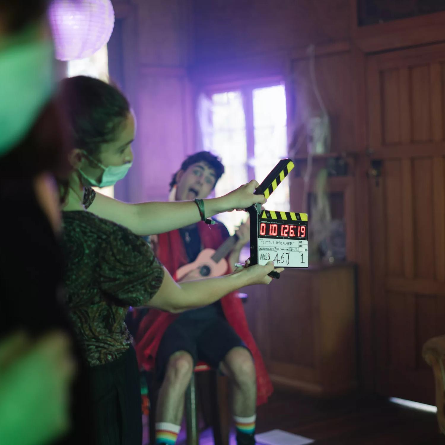 On the set of Little Apocolypse, where a set working is holding a clapper board in front of an actor pulling a funny face.