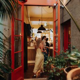 An open doorway connects a garden courtyard to a busy tavern.