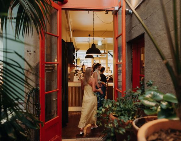 An open doorway connects a garden courtyard to a busy tavern.