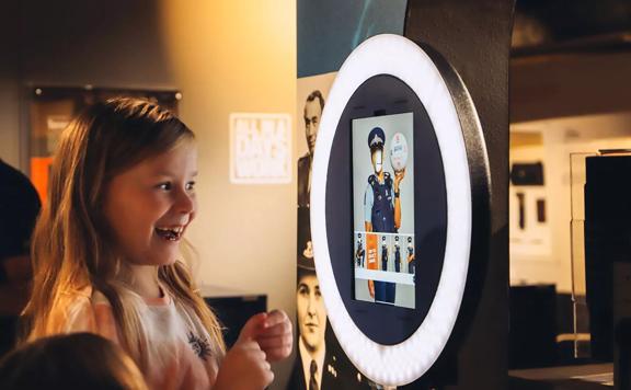 A young child playing with an interactive photo booth in the New Zealand Police Museum.