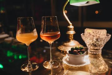 Two glasses of wine and a bowl of olives are on the stainless steel bar at Puffn Wine Bar in Wellington.