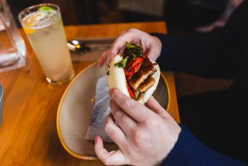Someone holding a pork belly bao.