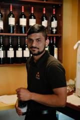 A waiter in a black shirt holding a bottle of wine.