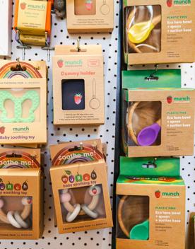A range of eco-baby toys hangs on a wall. They are in cardboard boxes.