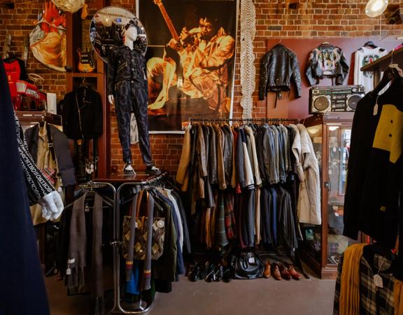 The moody interior of Hunters & Collectors, with racks of vintage clothes around the room and brick walls surrounding.