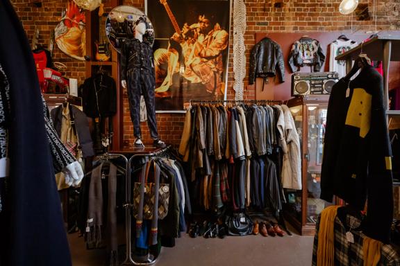 The moody interior of Hunters & Collectors, with racks of vintage clothes around the room and brick walls surrounding.