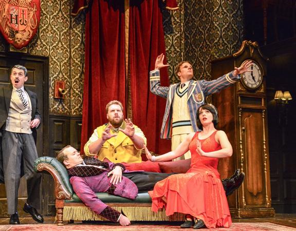 Five theatre actors are on stage performing a scene from 'The Play That Goes Wrong'.