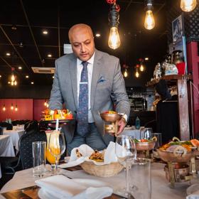 Waiter serving meals to a table inside Great India Restaurant.