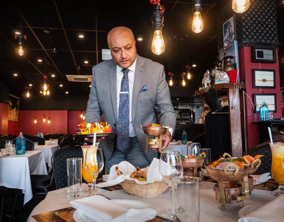 Waiter serving meals to a table inside Great India Restaurant.