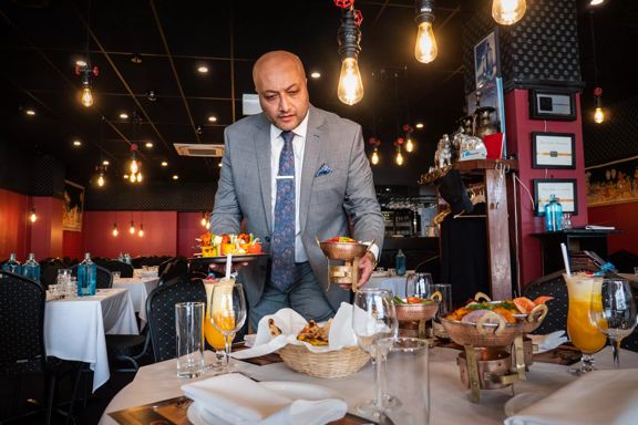 Waiter serving meals to a table inside Great India Restaurant.