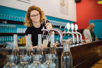 A worker at Chaat Street, an Indian tapas-style restaurant in Te Aro Wellington, is pouring a drink from a tap behind the counter.