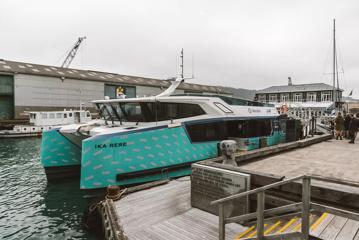 The teal-coloured Ika Rere electric ferry leaves parked at the Wellington Waterfront.