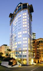 The exterior of the Bolton Hotel in Wellington Central is a silver, irregular shaped building with 16 floors.