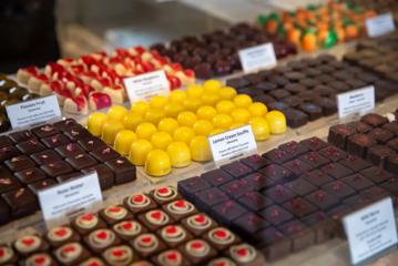 An array of choclates behind a glass cabinet at The Chocolate Story Petone. In focus, Lemon Cream Souffle.