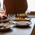 A table laden with plates of food with a glass of rosé wine and water glasses.