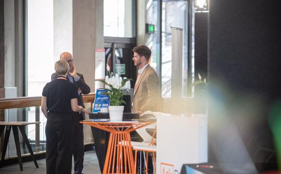 Three people standing around a table at the Michael Fowler Centre.