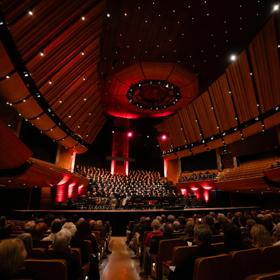 An orchestral choir wearing all black performs Handel's Messiah live on stage.