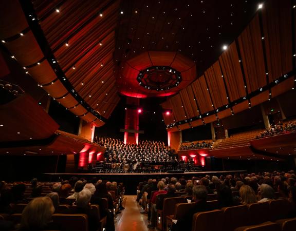 An orchestral choir wearing all black performs Handel's Messiah live on stage.