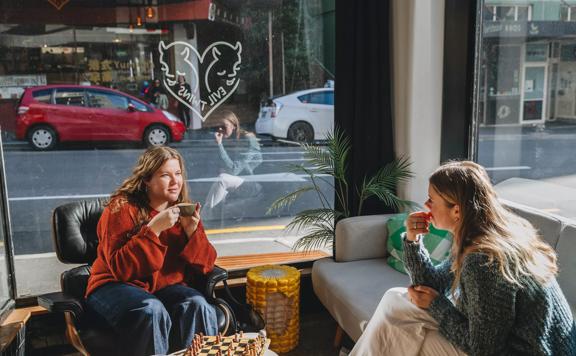 Two friends sit in the corner of Evil Twins Coffee playing chess. 