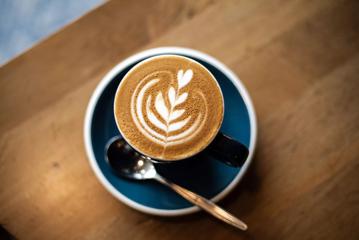 Close up shot of a coffee at Customs cafe, with foam art depicting a heart flower.