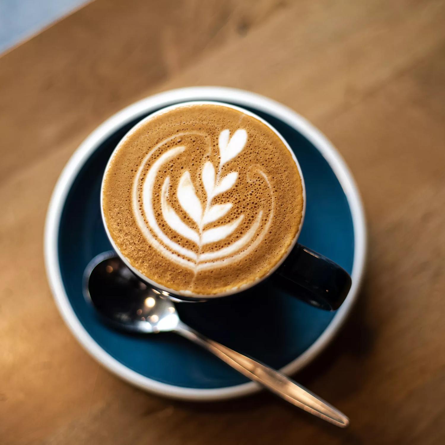 Close up shot of a coffee at Customs cafe, with foam art depicting a heart flower.