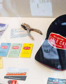 A display case at the Cable Car Museum in Kelburn, Wellington featuring a black baseball cap, old ticket books and brochures. 
