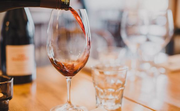 A glass of red wine is being poured.