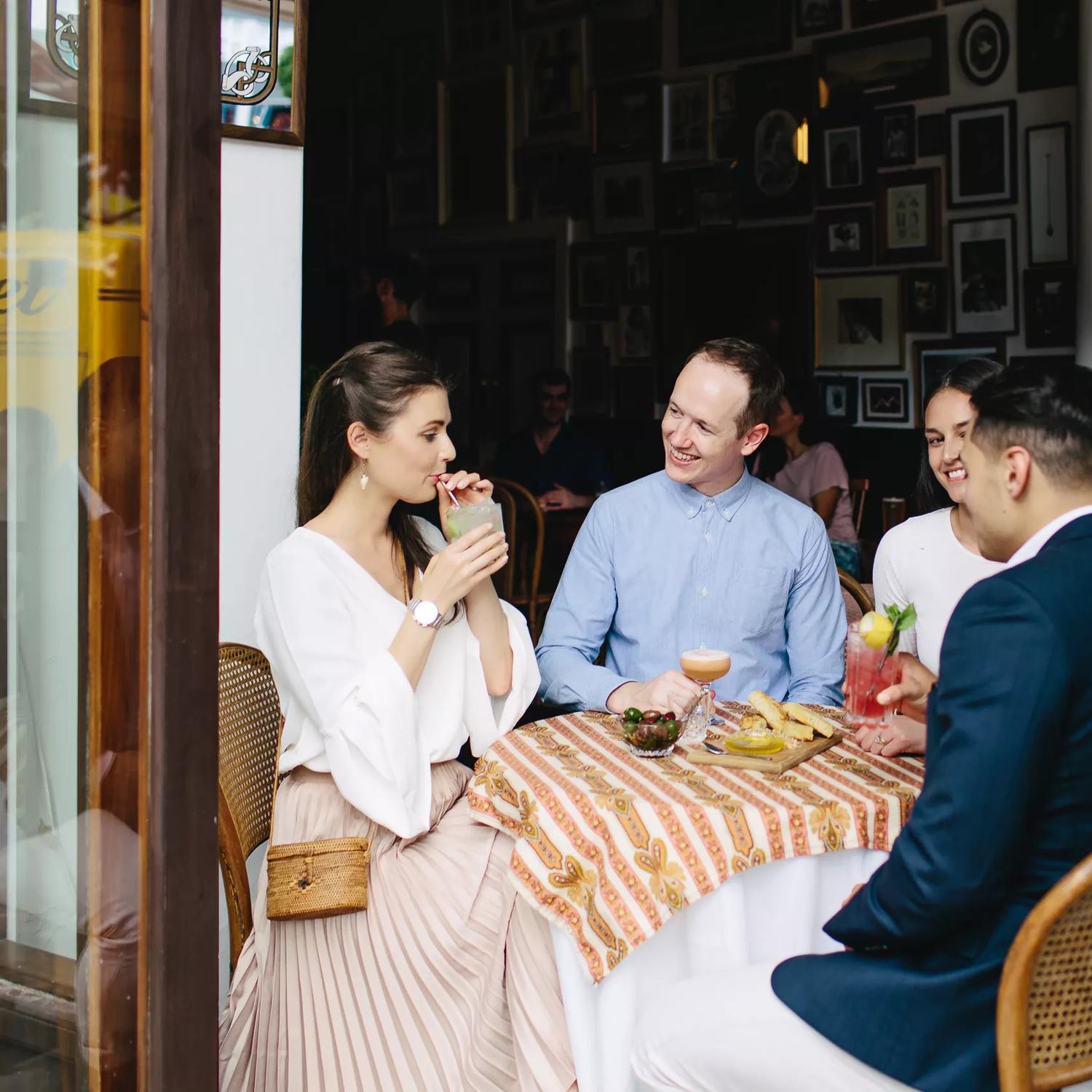 Four people enjoying cocktails and appetizers at Crumpet, a cosy café and bar nestled in the Opera House, on Manners Street in Te Aro, Wellington.