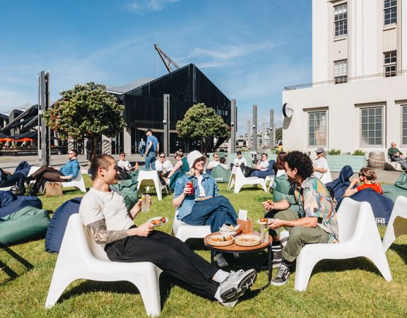 Three friends enjoy food and drinks al fresco at St Johns Bar on Wellington's Waterfront.