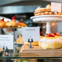 The pastry window at Tomboy Bakery, located in Mount Victoria in Wellington. A small white card fixed to a silver stand says "Custard Brioche".