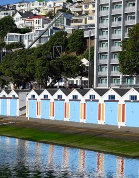 The screen location of Oriental Bay, wth pastel-coloured, Art Deco apartments, brightly-painted boat sheds, and the golden beach.