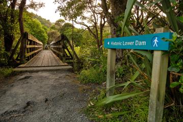 The sign for Historic Lower Dam pointing towards a bridge on the Gums loop.