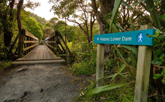 The sign for Historic Lower Dam pointing towards a bridge on the Gums loop.