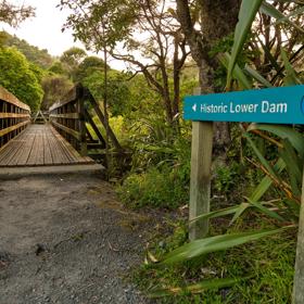 The sign for Historic Lower Dam pointing towards a bridge on the Gums loop.