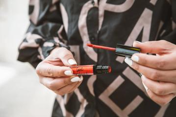 A pair of hands holding a Gil Native branded lip gloss. 