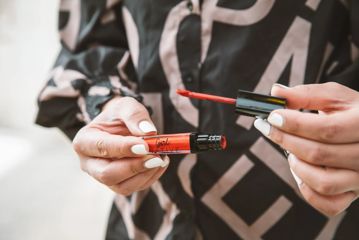 A pair of hands holding a Gil Native branded lip gloss.